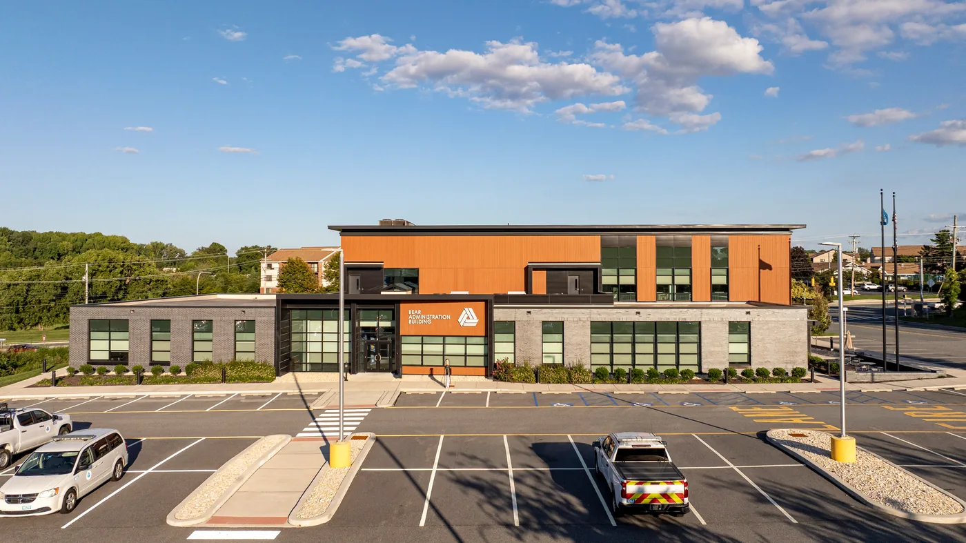 Elevated front view of the administration building at golden hour, wood look cladding above dark and light brick