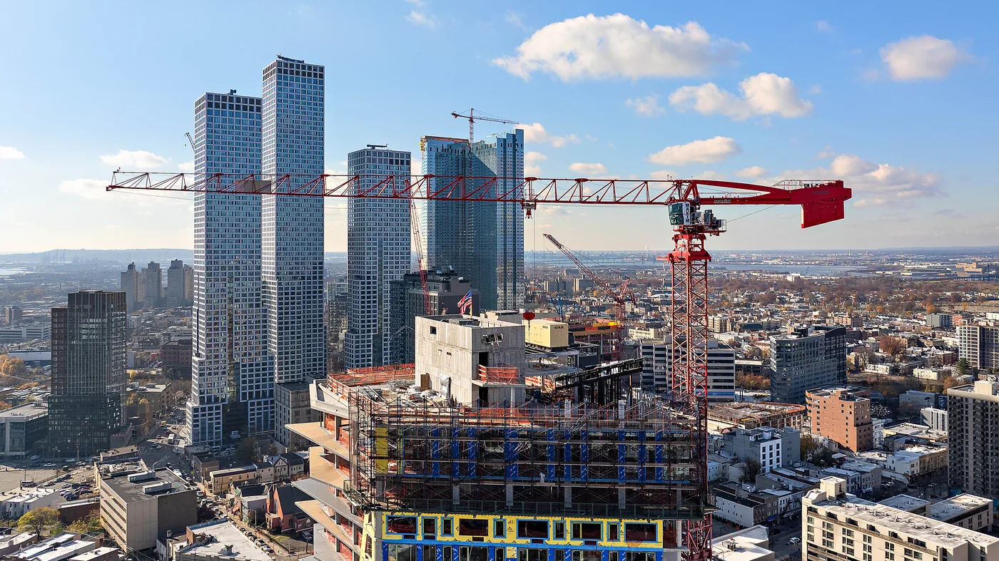 Tower crane working above a concrete frame beside four glass high rises