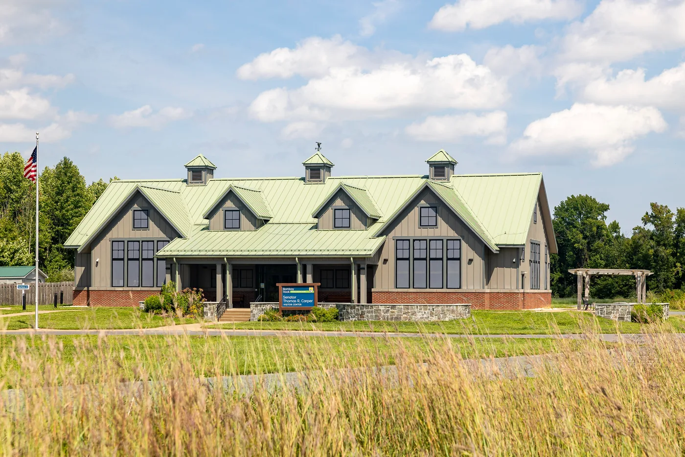 Bombay Hook visitor center with a green standing seam roof, seen across tall meadow grass