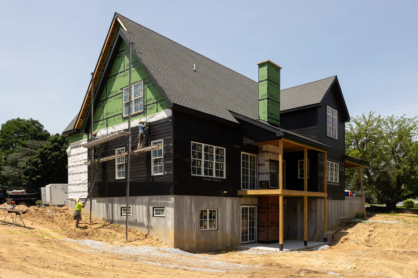 Crew on scaffolding installing dark lap siding on a new two story home