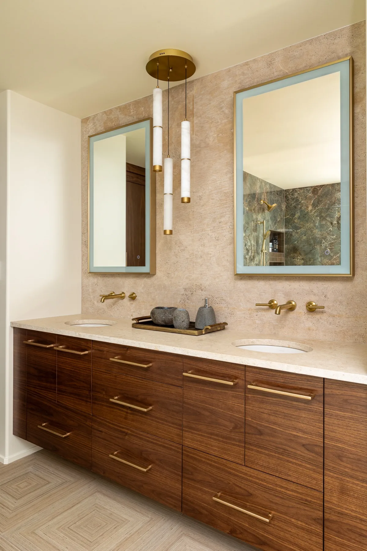 Walnut vanity with brass fixtures, backlit mirrors and alabaster pendants