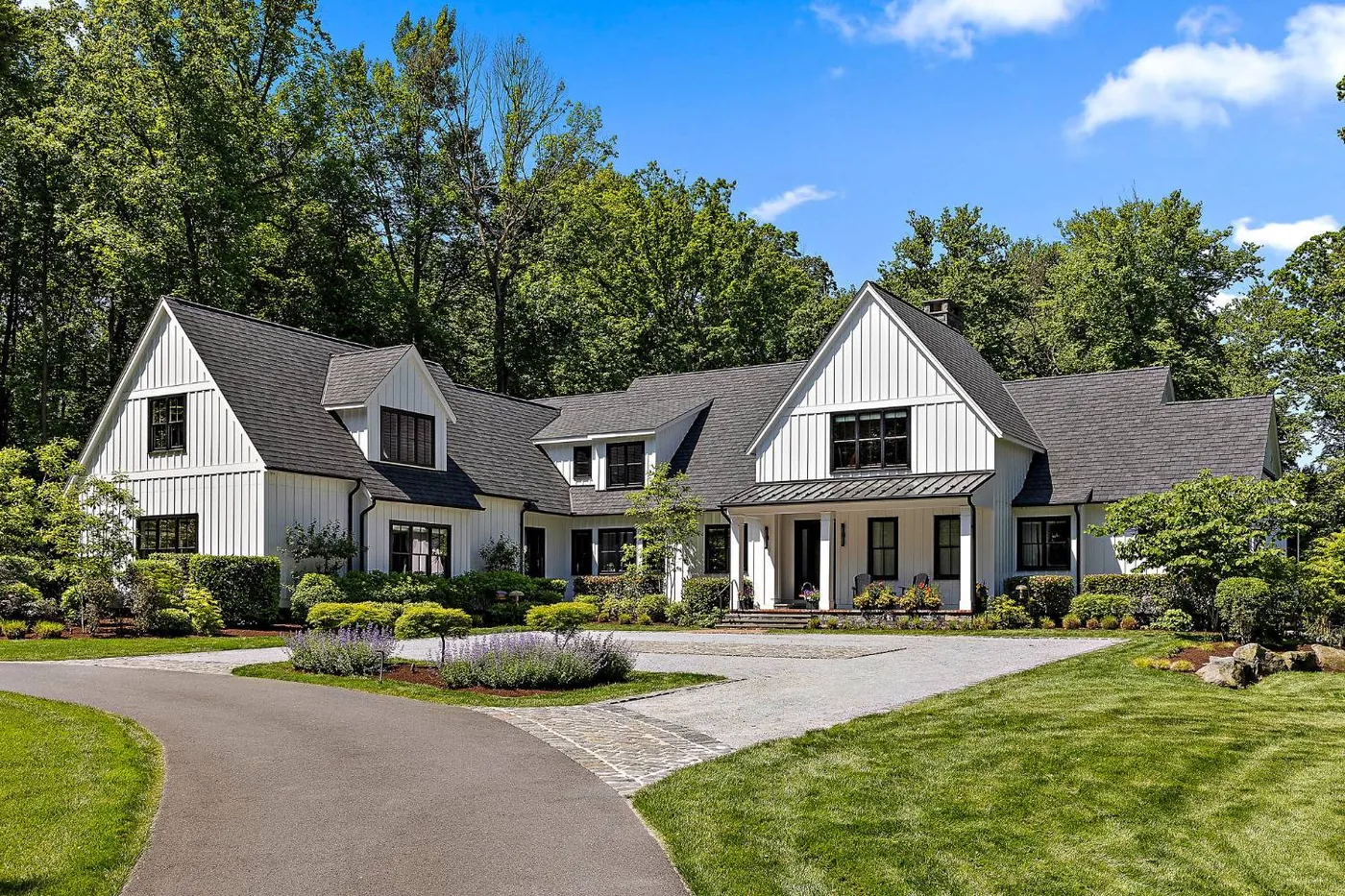 White board and batten modern farmhouse at the end of a curving drive and gravel motor court