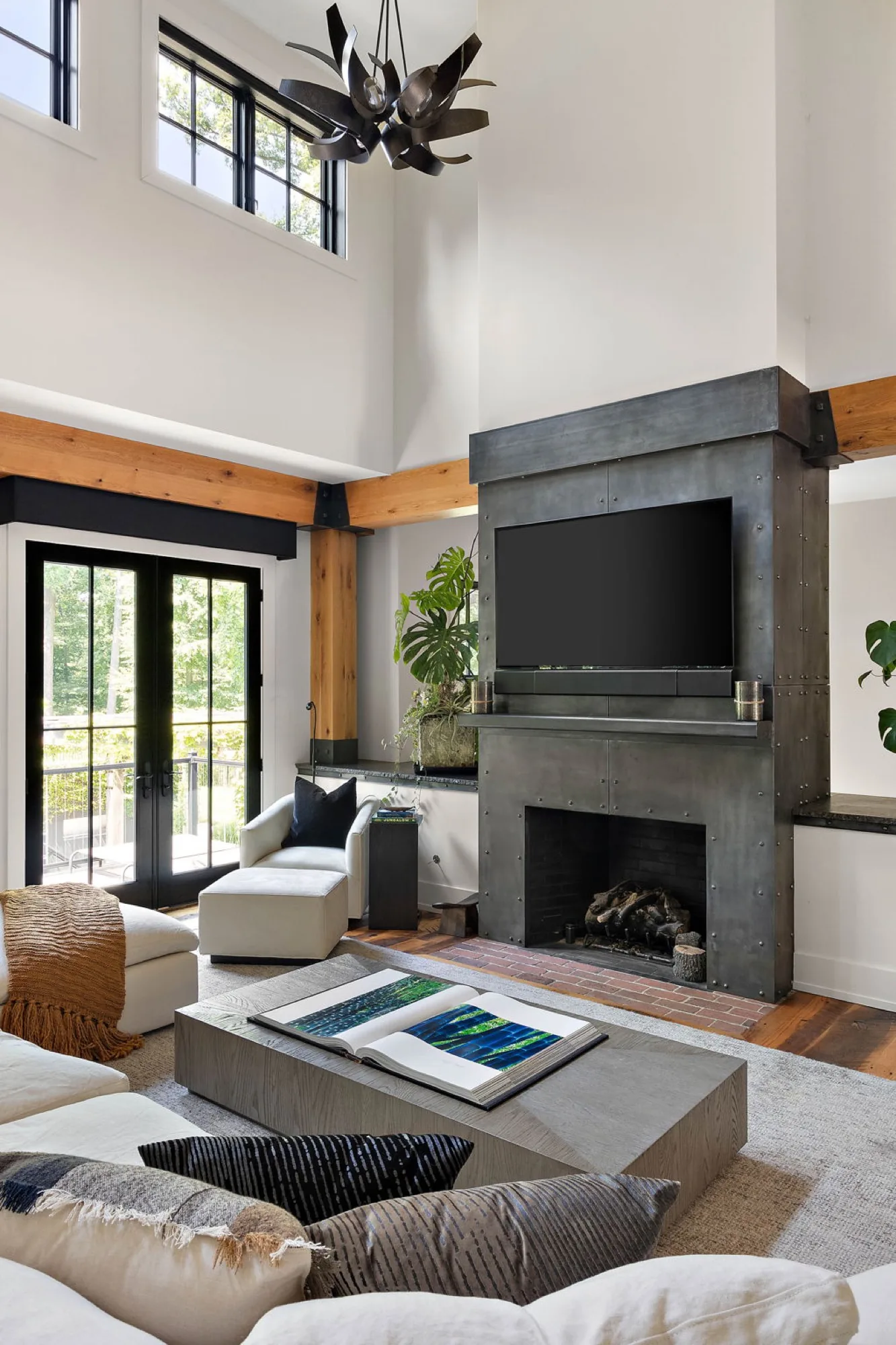 Double height great room with a steel clad fireplace and timber beams