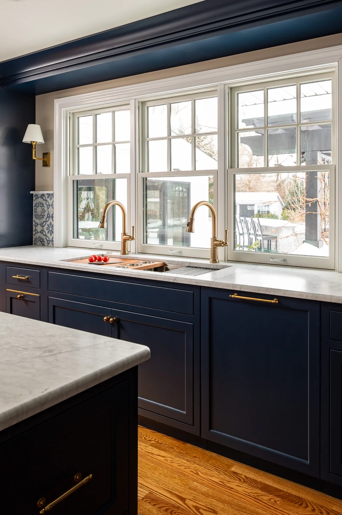 Navy cabinetry and marble counter beneath a bright window