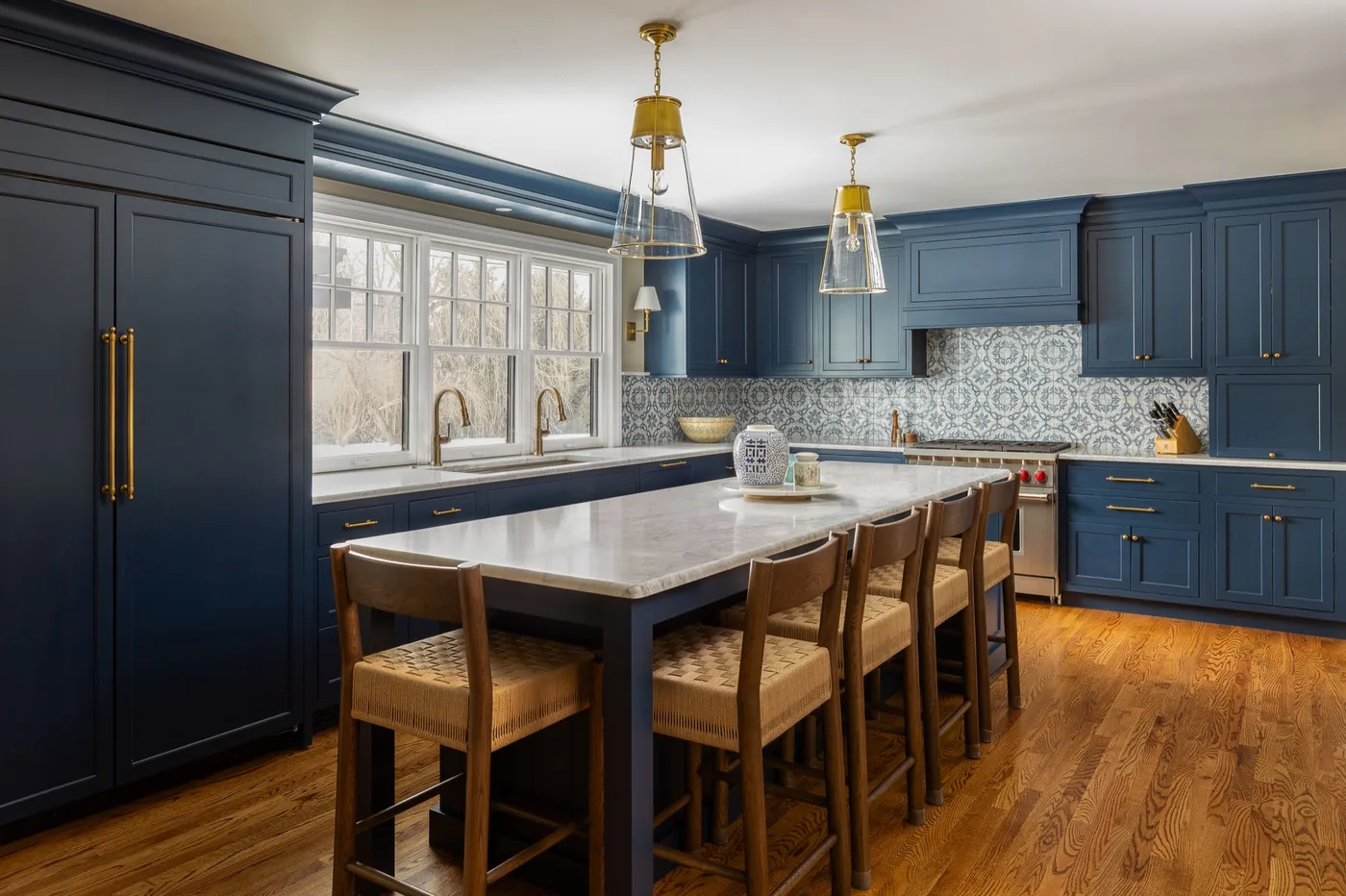Navy kitchen with brass pendants, patterned tile and a long island